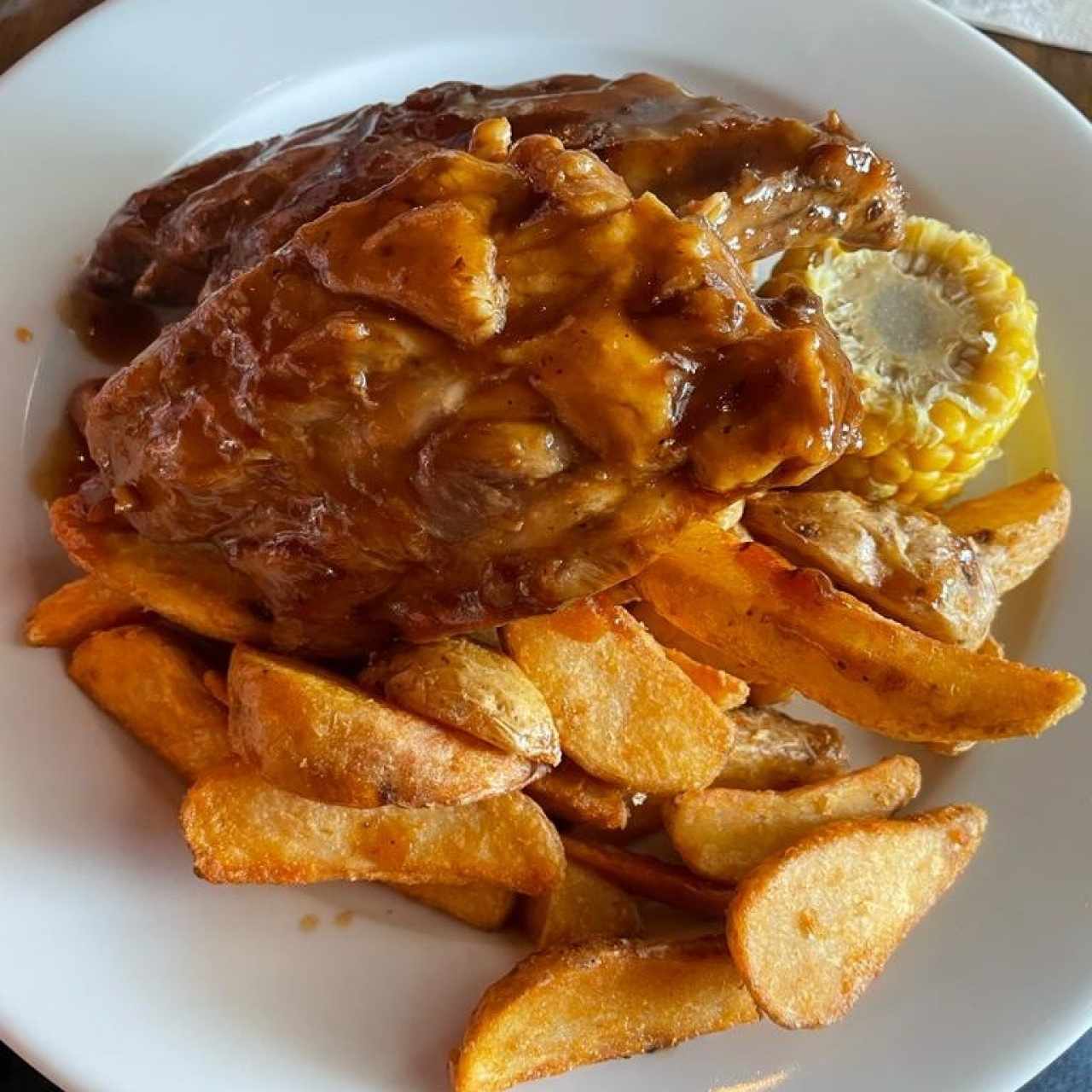 COSTILLAS CARIBEÑAS (Costillas de Puerco, en Nuestra Salsa Barbacoa con Miel de Caña y Papaya, servidas con papas en gajos y una mazorca)