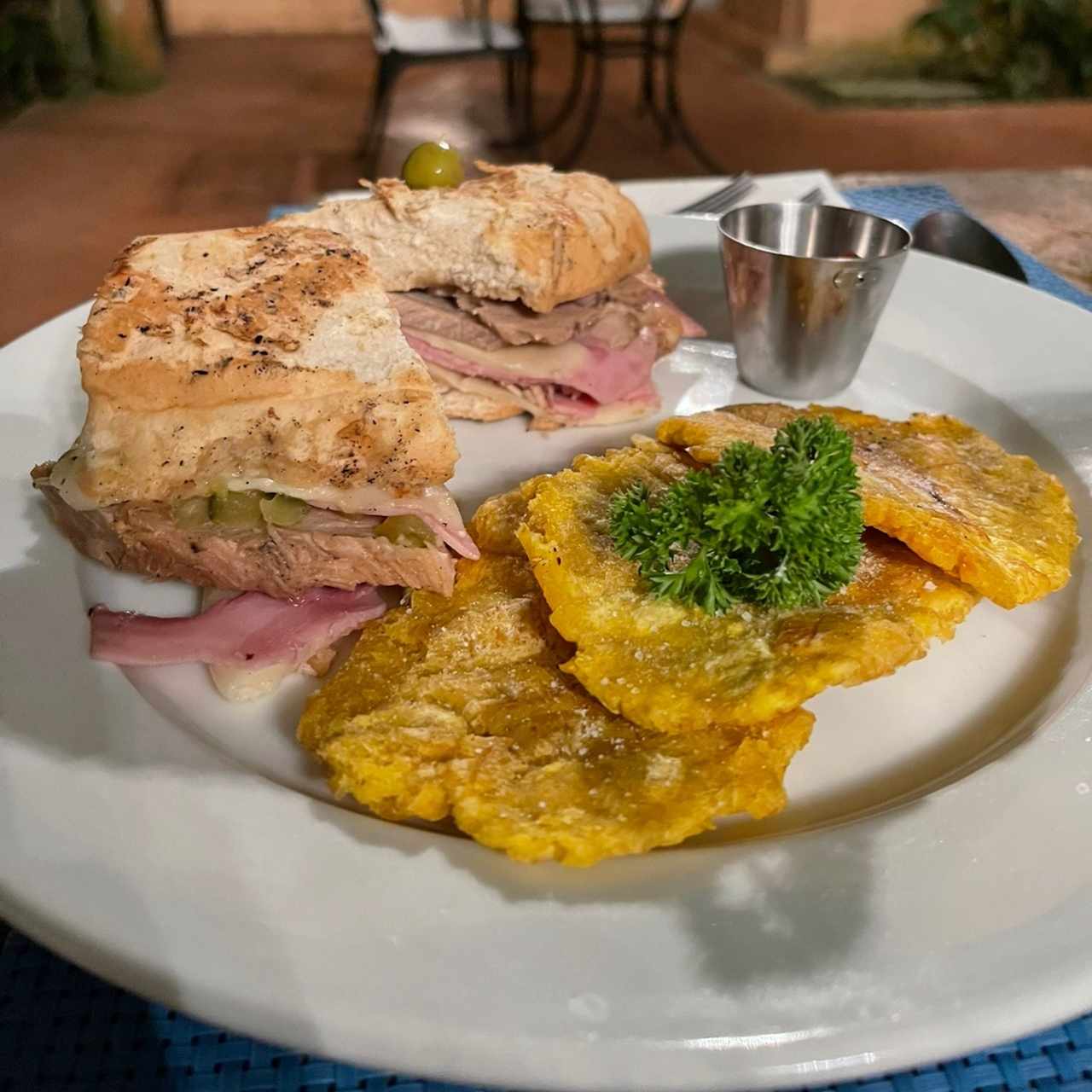 Sandwich Cubano: Pernil, Jamón, queso suizo y pepinillo con tostones de plátano, pan francés
