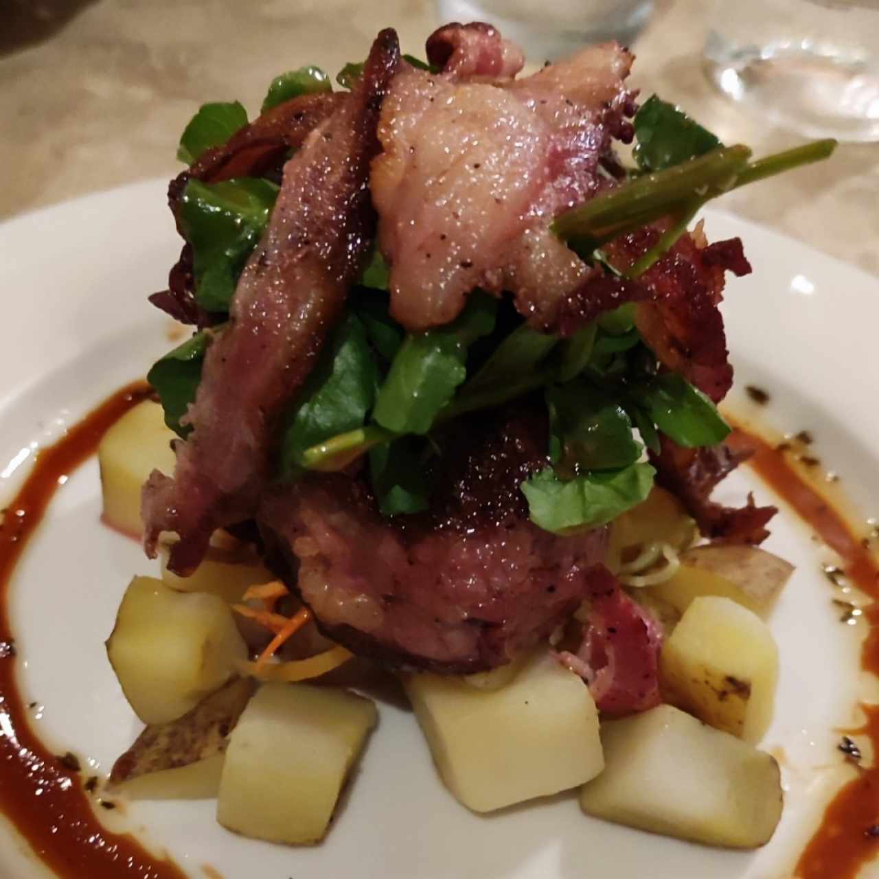 Tournedo con tocino, berro tibio, vegetales al hilo y papitas