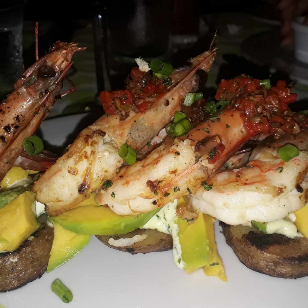 Langostinos a la grilla con chimichurri de ajíes, aguacate, aceitunas griegas y alcaparras