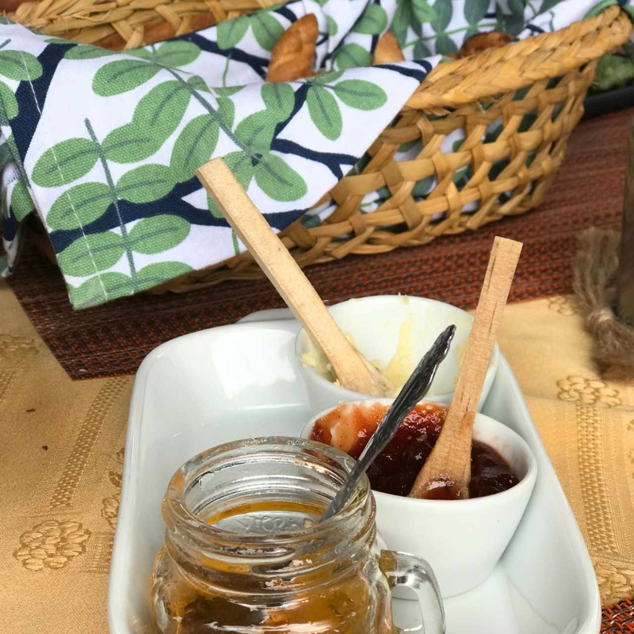 canasta de pan de desayuno con miel, mermelada y mantequilla lavada.
