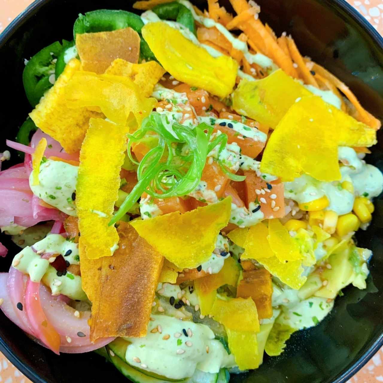 Poke de salmón, aguacate, zanahoria. maiz, cebolla, jalapeño y pepino con plataninas y salsa de aguacate y jalapeño
