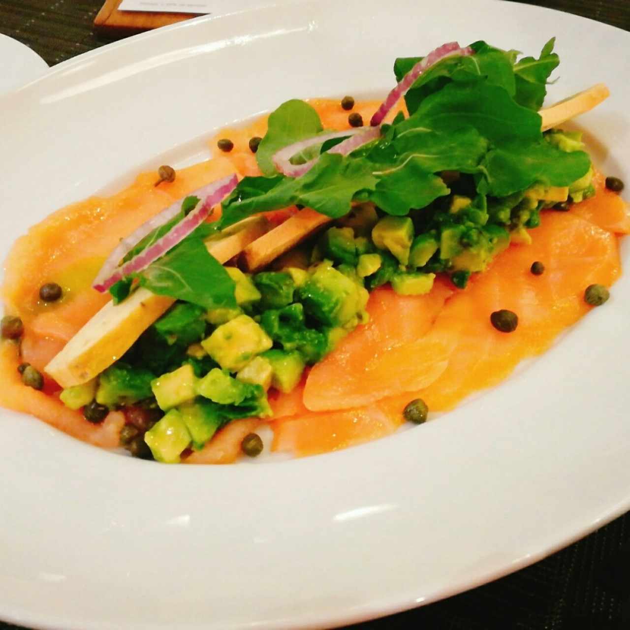 Carpaccio de salmón ahumado con aguacate, limón, aceite de oliva y arúgula