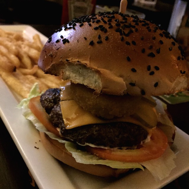 Hamburguesa de la casa con aros de cebolla y cebollas caramelizas en Guiness.