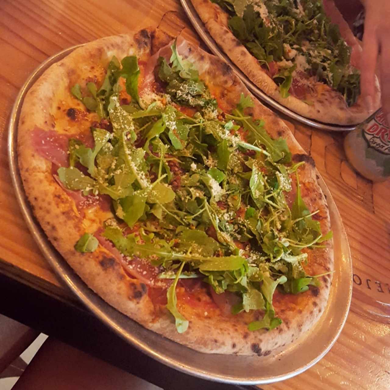Pizza con arugula, jamon serrano, parmesano, oregano y aceite de trufas.