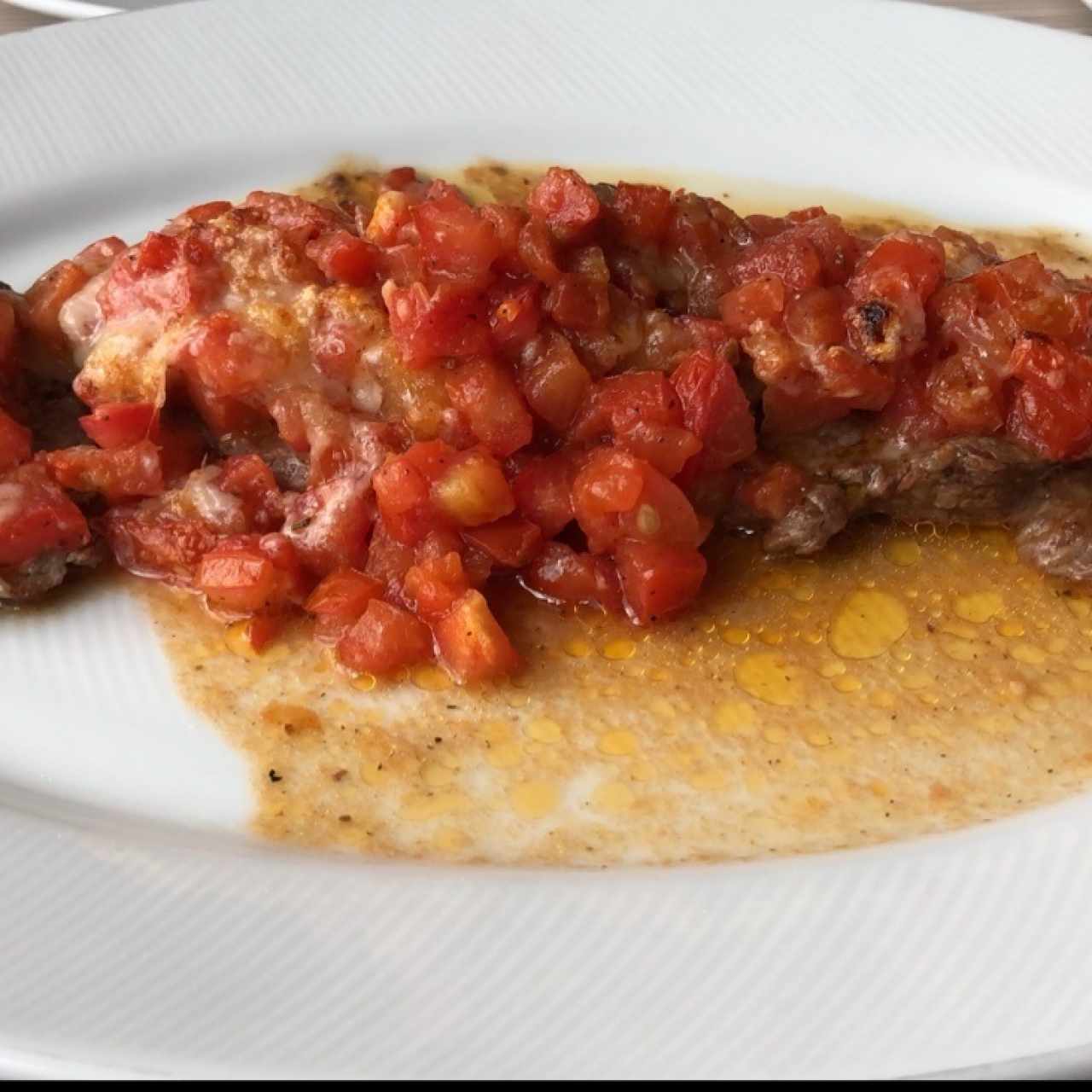 Filete de res bañando con tomates, ajo y parmersano