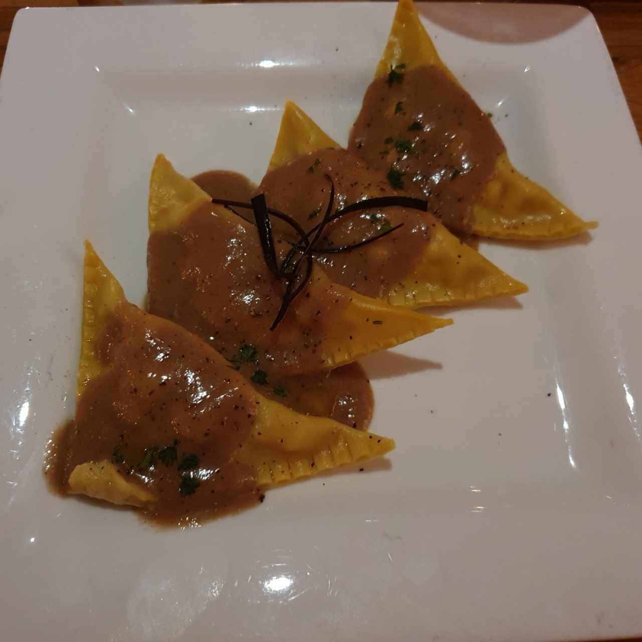 Raviolis de pasta wonton rellenos de camarón y corvina con salsa de hongos y aceite de trufa