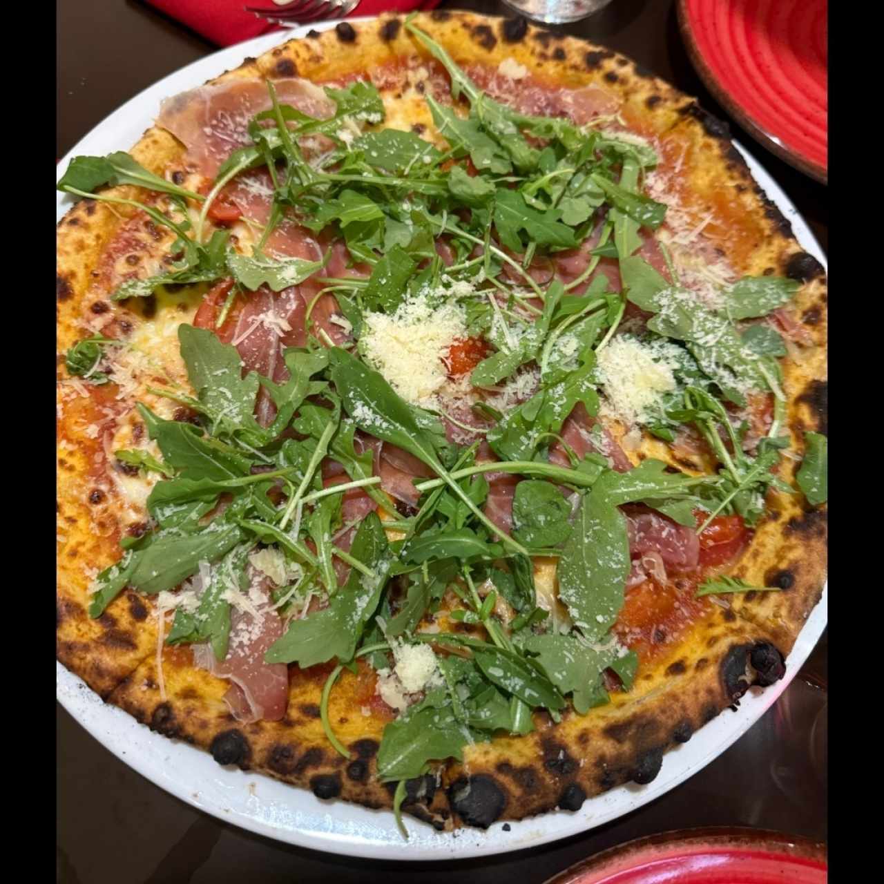 Pizza de prosciutto y arúgula en salsa roja