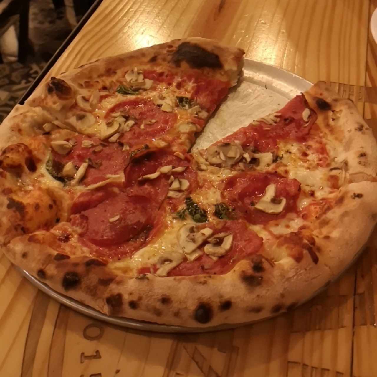 Pizza de pepperoni con hongos y albahaca