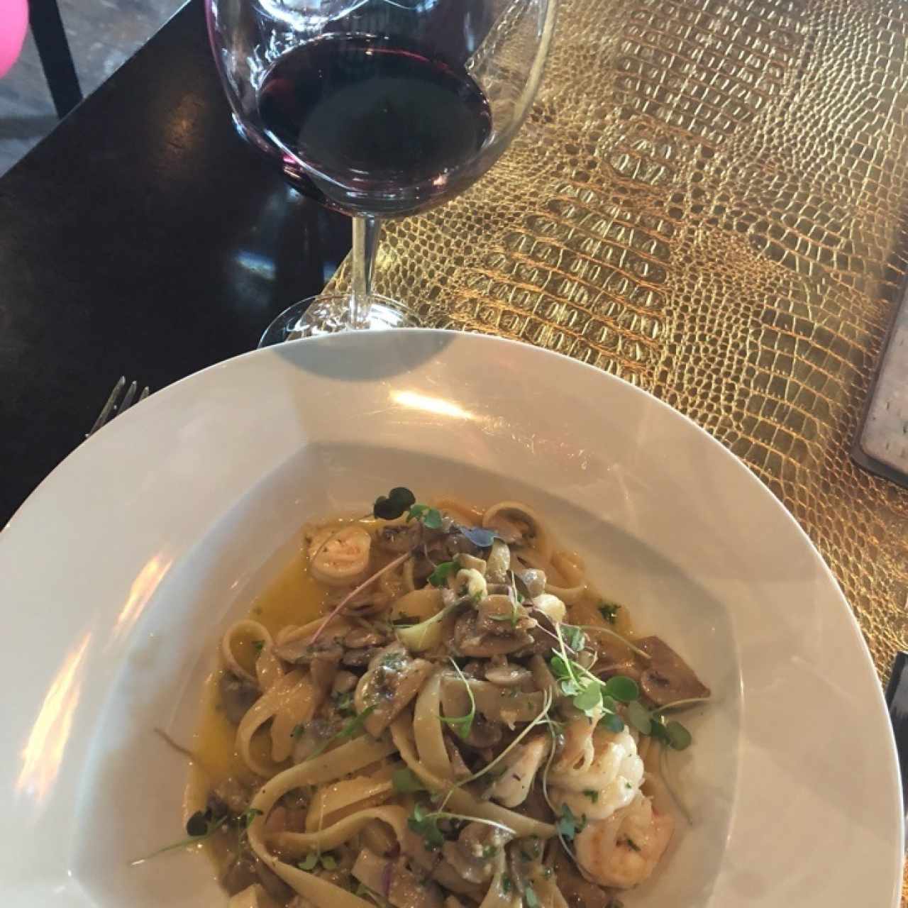pasta al oleo con camarones acompañado de una copa de vino argentino