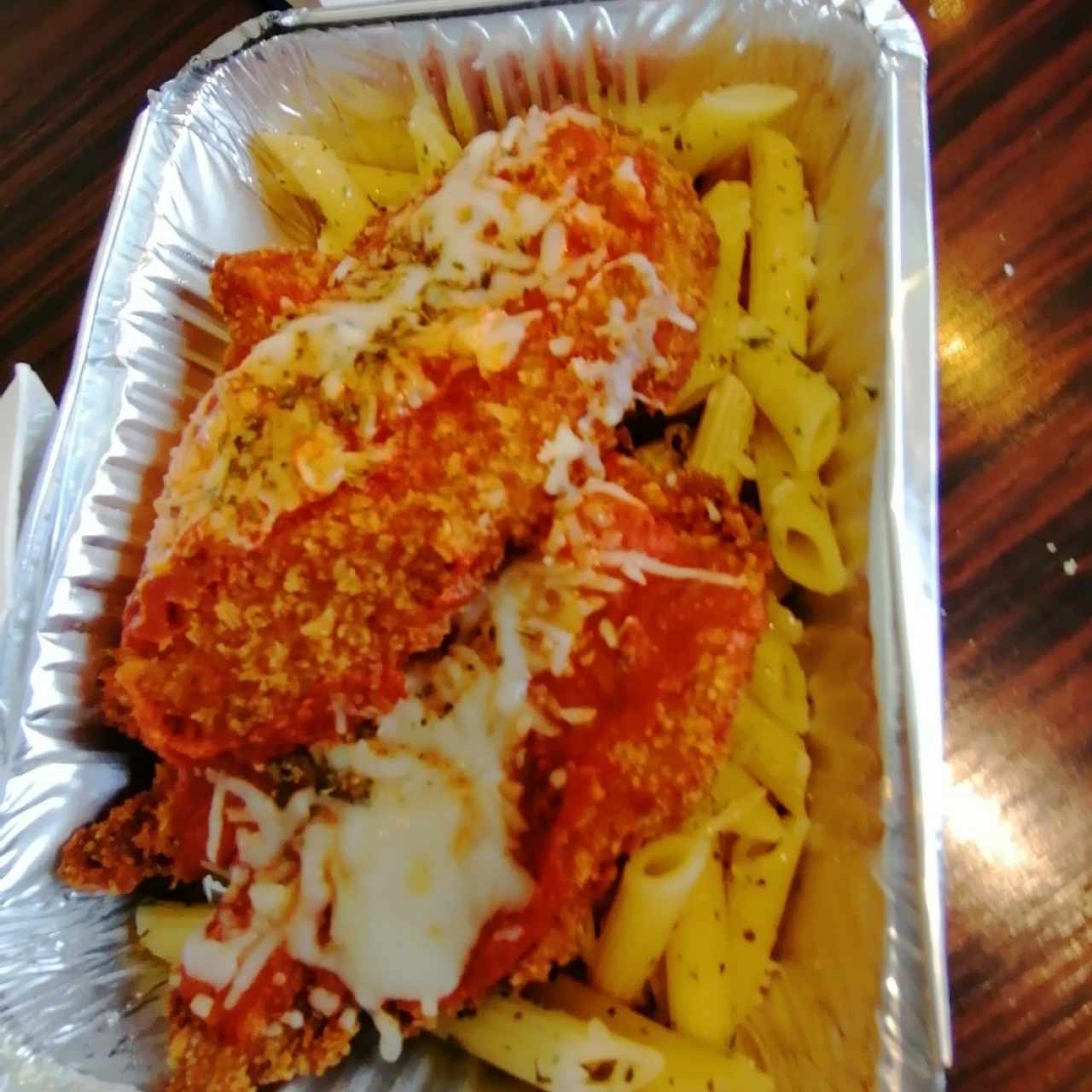 Pollo a la parmesana acompañado de penne al olio y pan con ajo