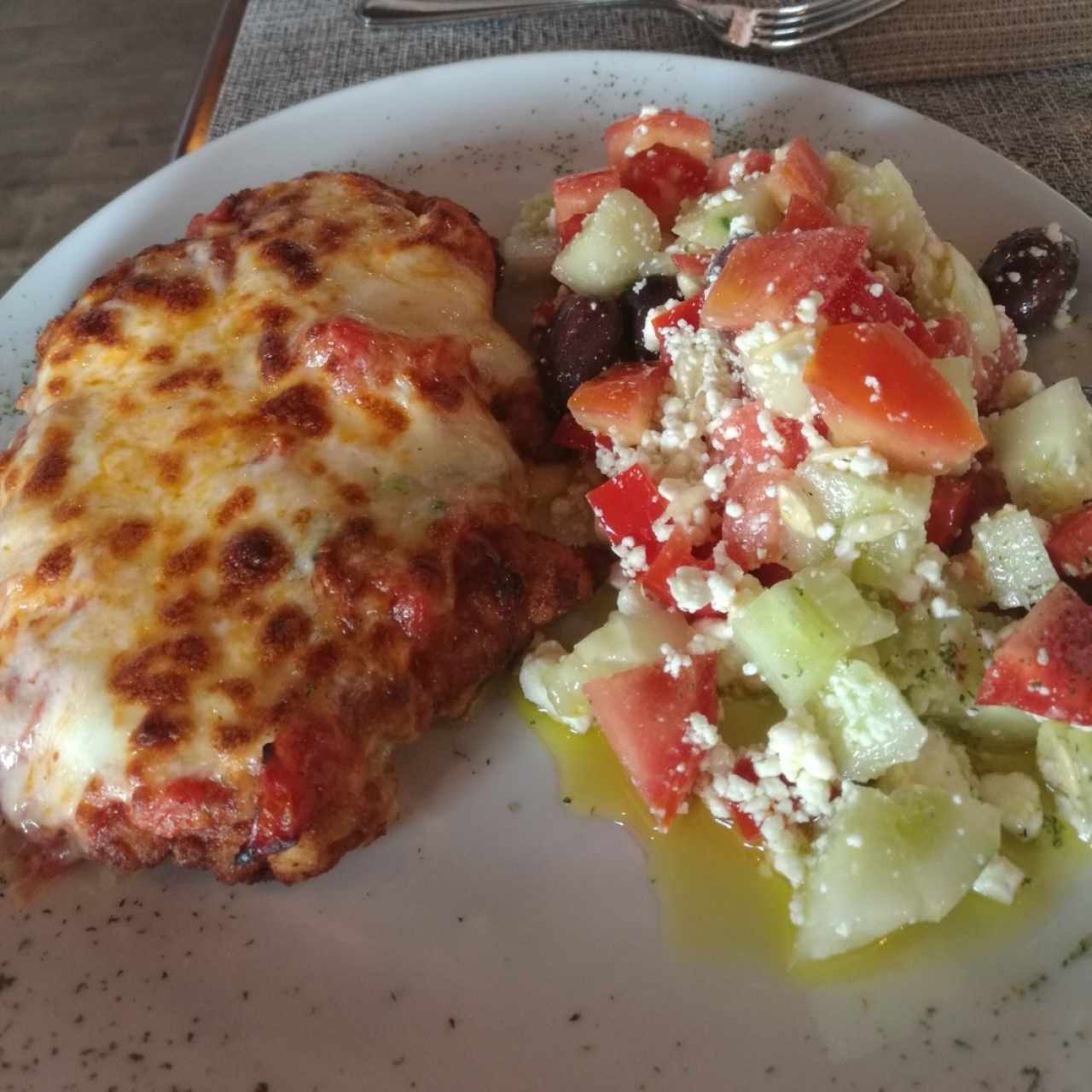 Pollo a la parmesana con ensalada griega.