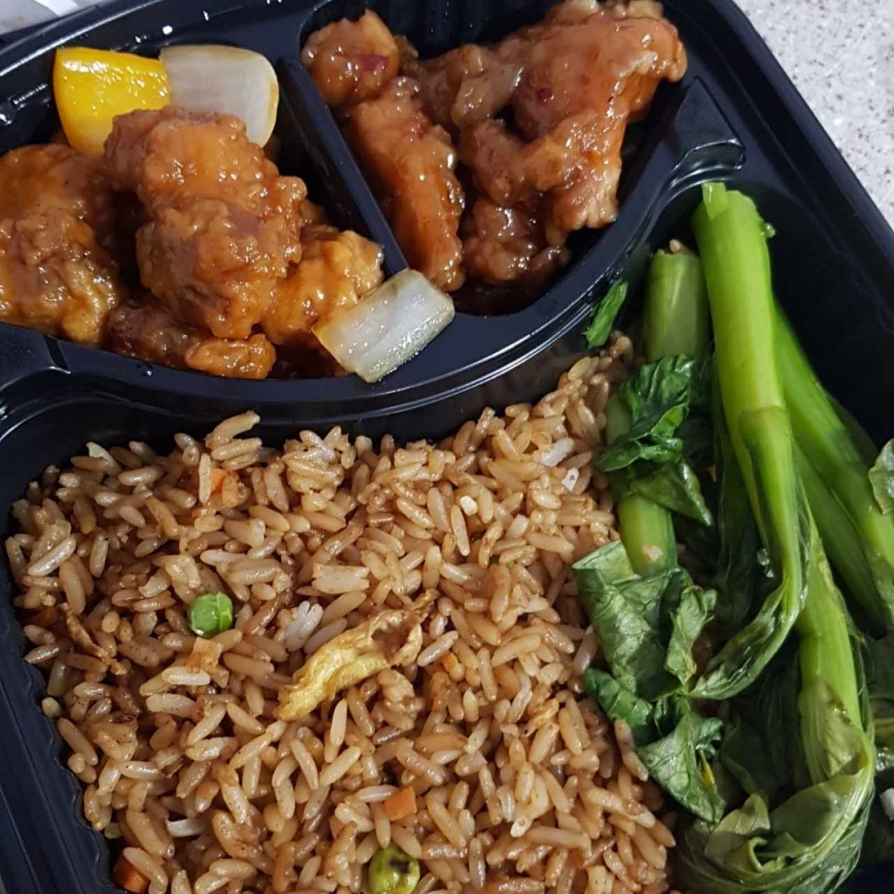 Opción para llevar, pollo al sésamo y pollo tso acompañado de arroz frito y hojas de mostaza 