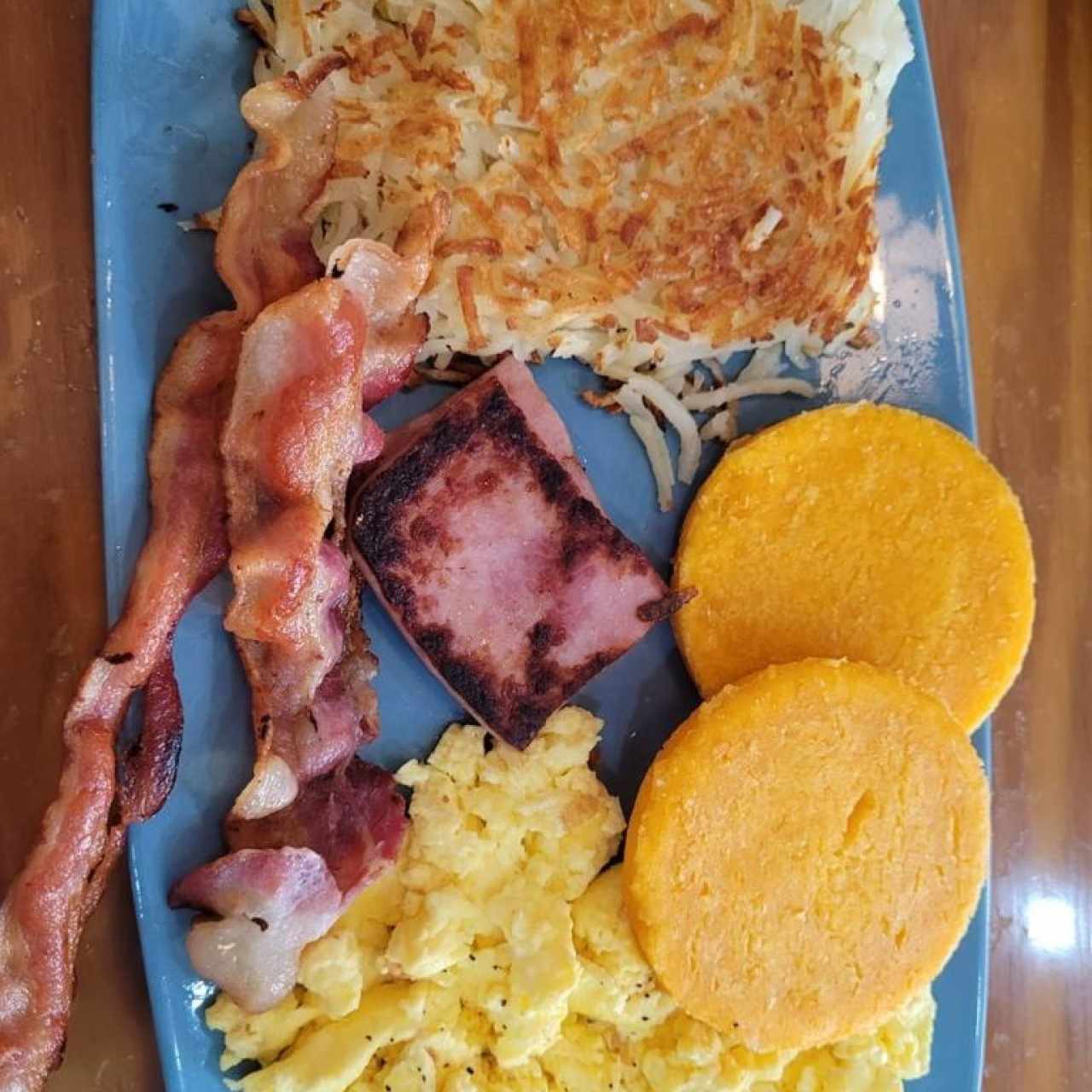 Desayuno Sampler (Dos huevos, papas hash browns, dos tiras de tocino, dos salchichas y dos rebanadas de jamón)
