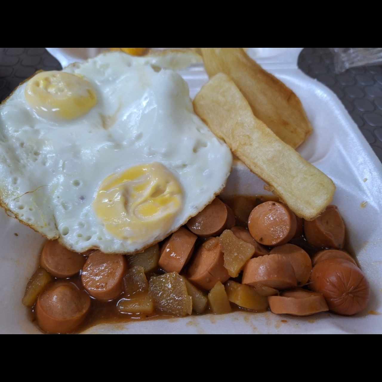 par de huevos fritos con salchicha guisada y yucas fritas.