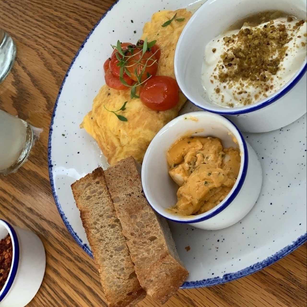 omelette con tomates ahumados relleno de queso de cabra, mantequilla de la casa, pan brioche y yogurt con piñas asadas y pistachos