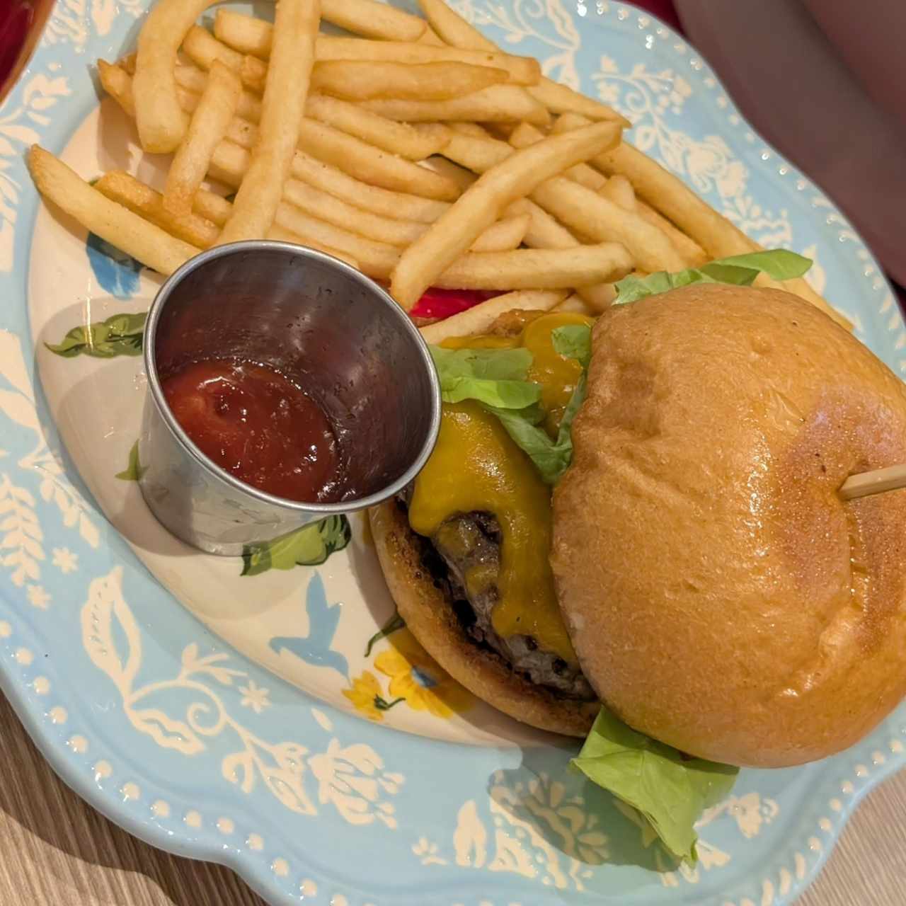 Burger con queso cheddar, cebolla caramelizada, tomate y papas fritas. 