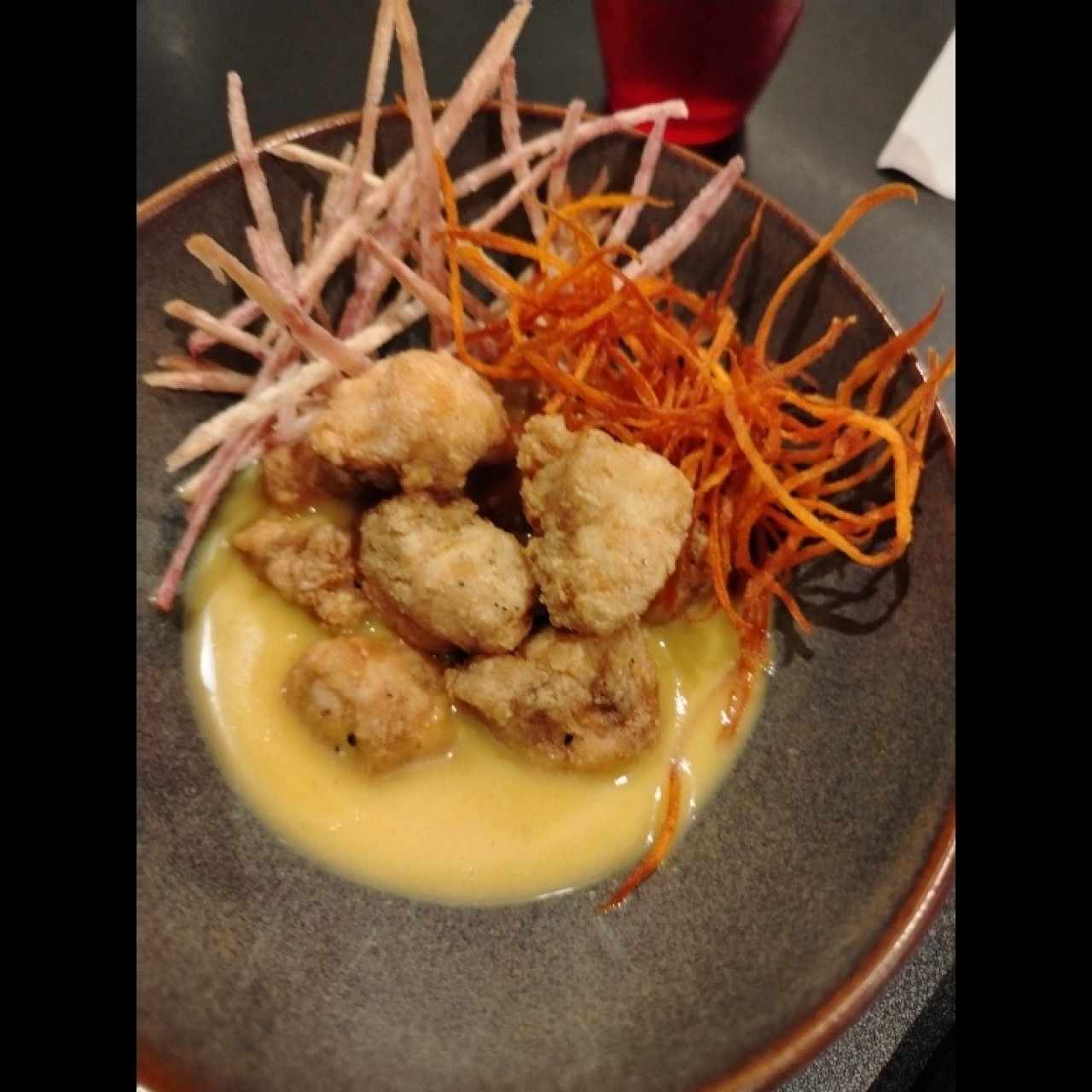 Ceviche de pescado frito en reducción de leche de coco, jengibre y maracuyá con un toque de hierba buena