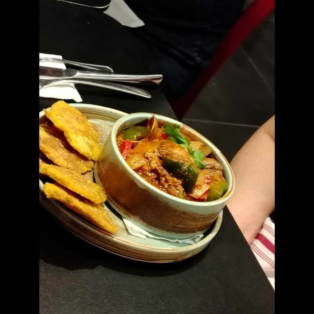 Estofado de mariscos salteados con vegetales frescos en salsa criolla, acompañado de crujientes patacones