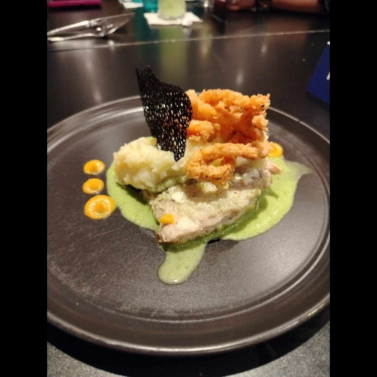 Filete de corvina al vapor con ajillo de recao verde y anillos de calamar con tope de puré de papas y puerros