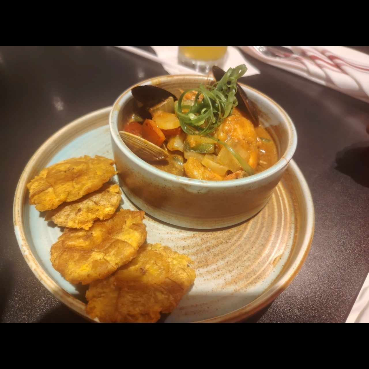 Estofado de mariscos salteados con vegetales frescos en salsa criolla, acompañado de crujientes patacones