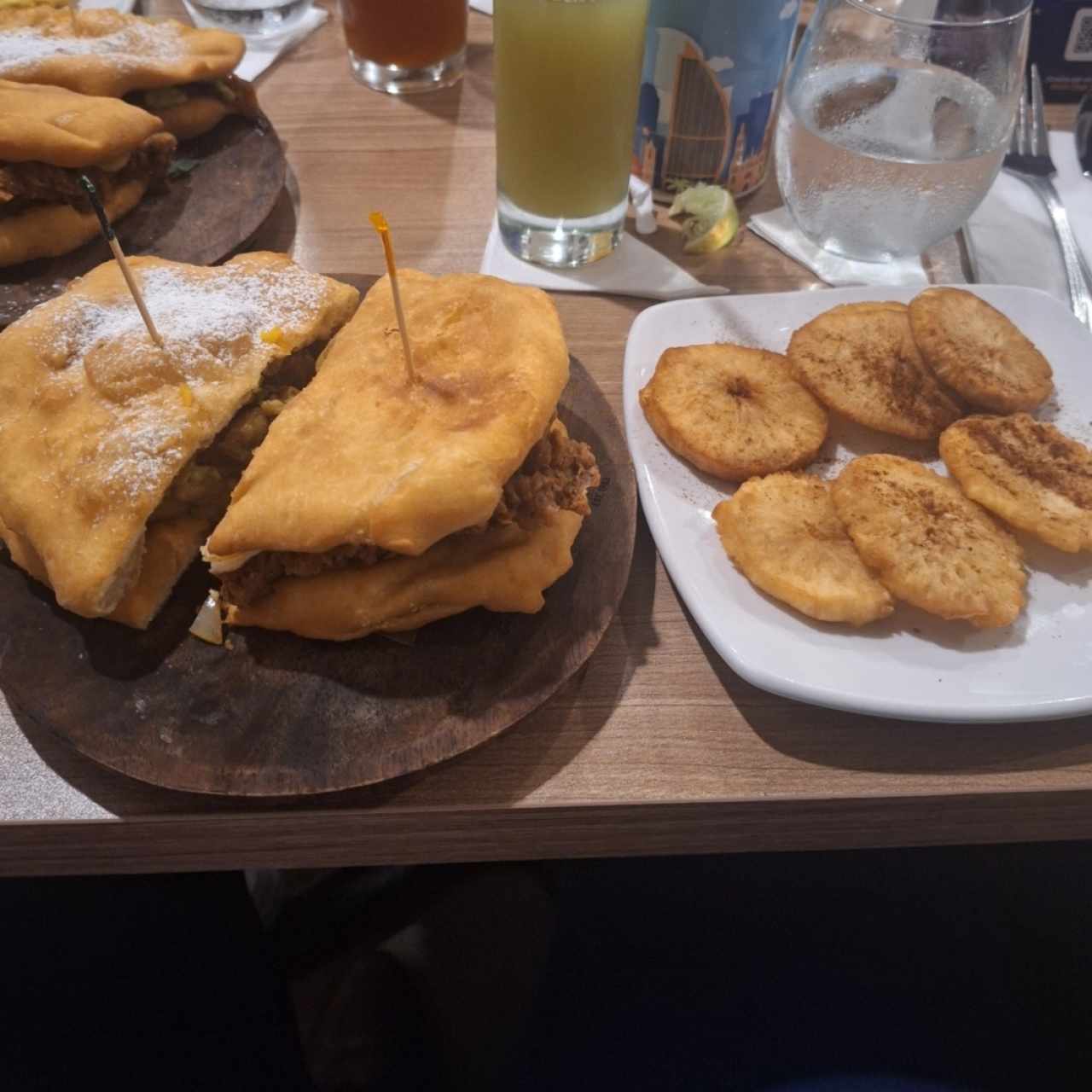 Es una mita de emperedado porkbelly una mitad de emparedado patriota, junto con patacones de yuca y guapo (jugo de caña).