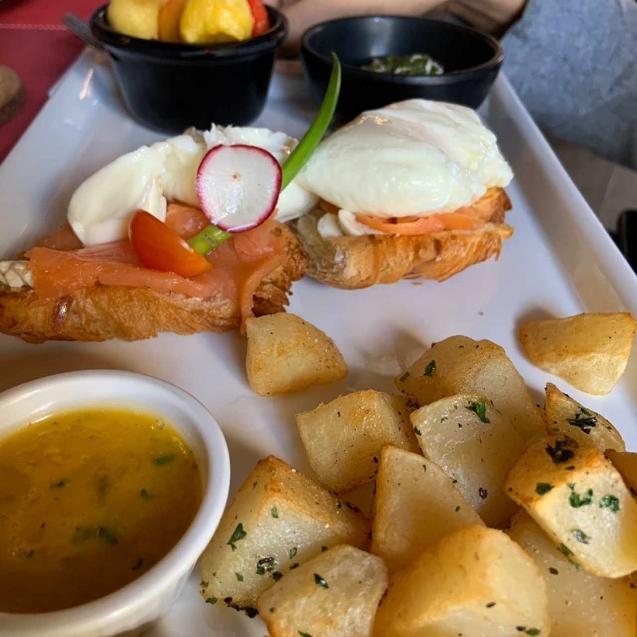 huevos benedictinos con salmo sobre croissant, frutas, papas, jugo y café