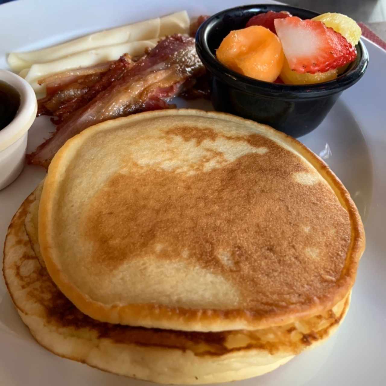 Pancakes con sirope ó chocolate ó miel, tocino, queso, frutas, jugo, café