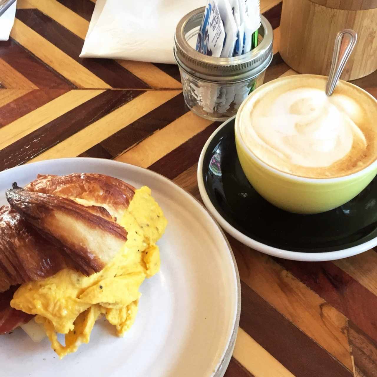 delicioso desayuno, corissant con huevo revuelto, tocino y queso. y un capuchino