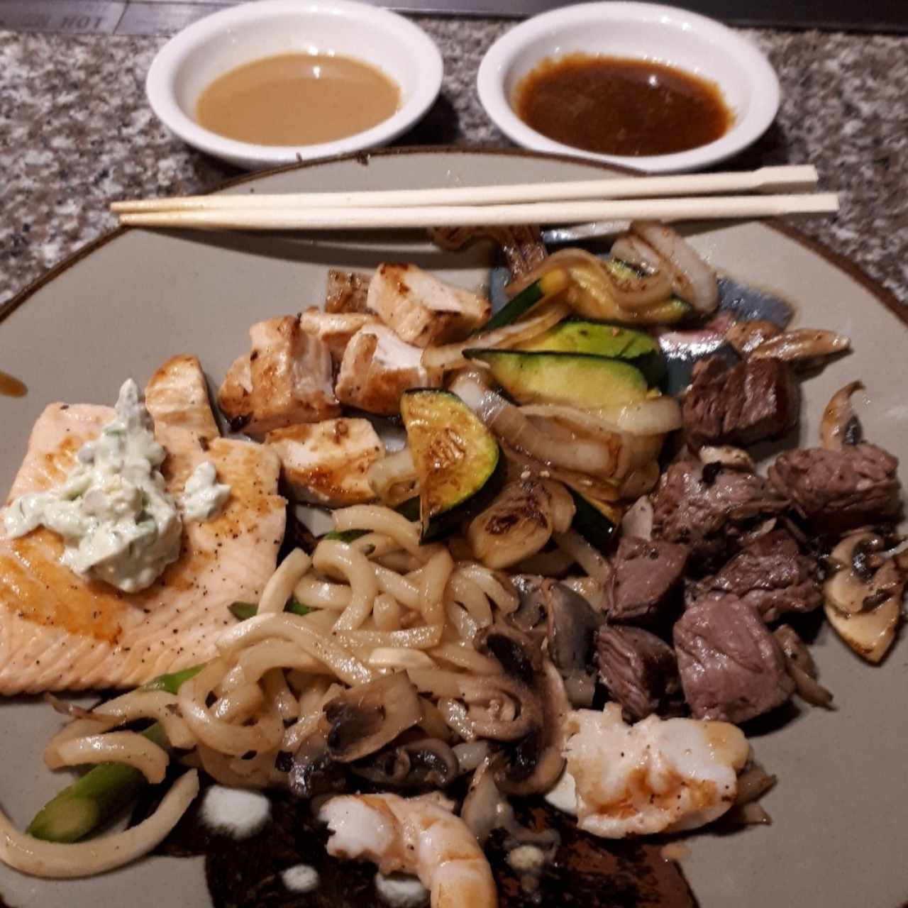 salmon con espárragos, carne y pollo teriyaki fideos y vegetales salteados para compartir. Al fondo salsa de ostras y jengibre 