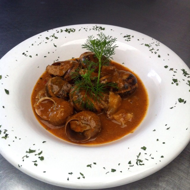 Caracoles con conejo y mano de cerdo en salsa tierra roja