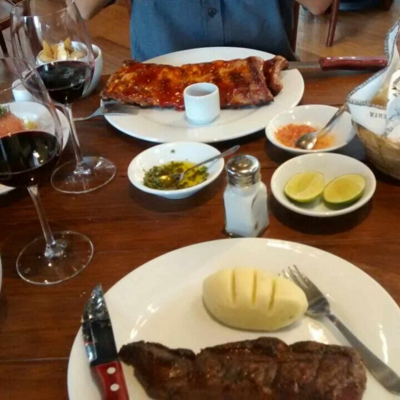 Pan de cortesía, punta de anca termino medio, puré de papa con queso azul, baby back ribs (700grs), copa de Merlot y Carmenère