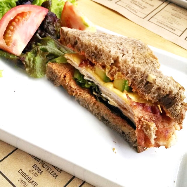Sándwich de pavo, tocino, aguacate, queso y salsa romesco en pan de nueces y uvas