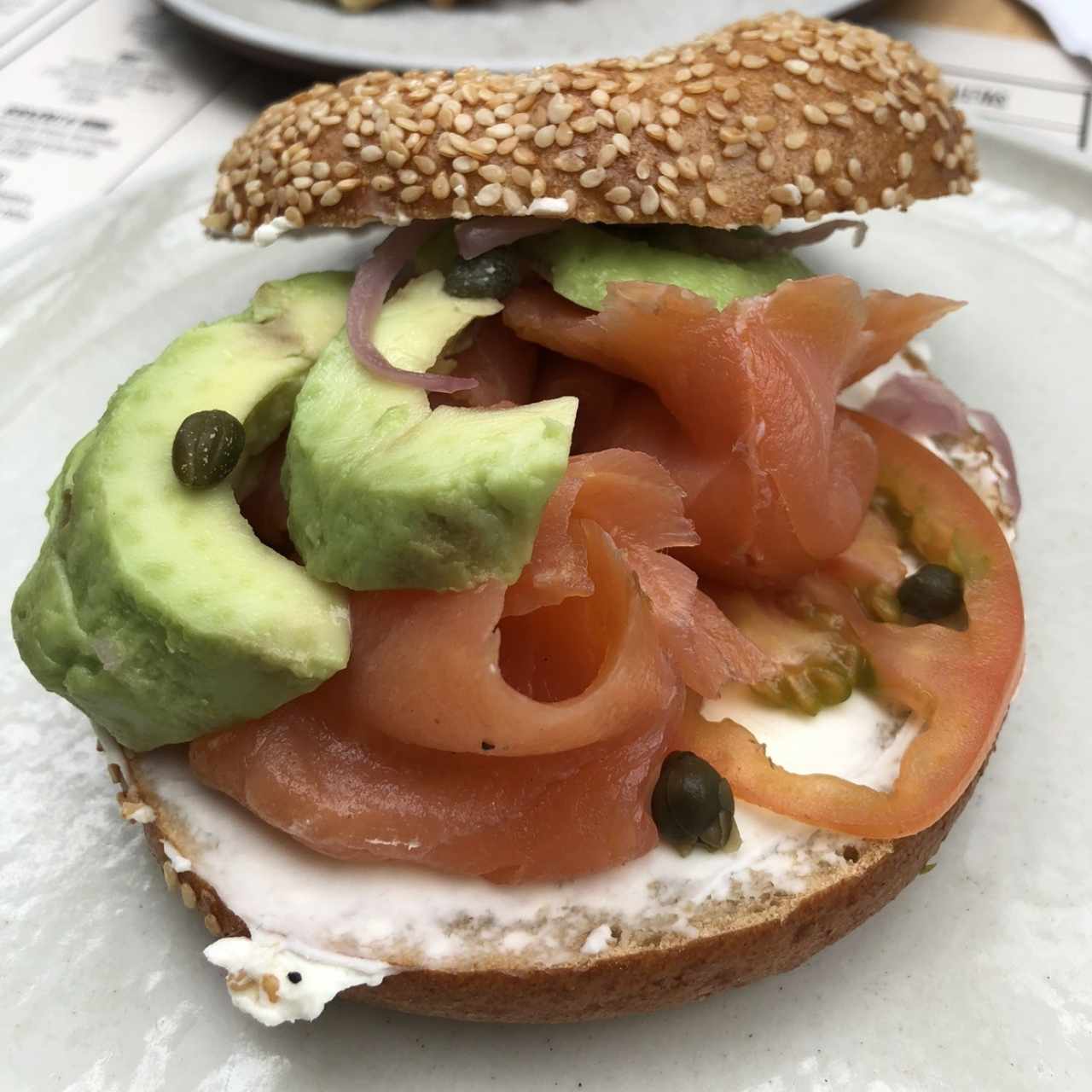 Bagel con salmón ahumado, aguacate, queso crema y alcaparras 