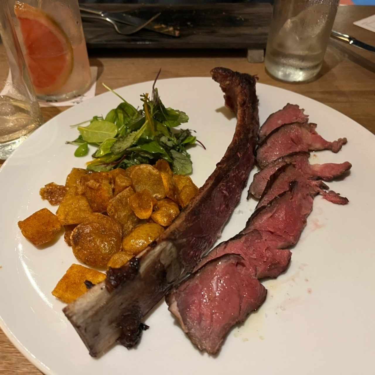 Asado de tira a baja temperatura, mantequilla de ajo negro y pellejos de papa