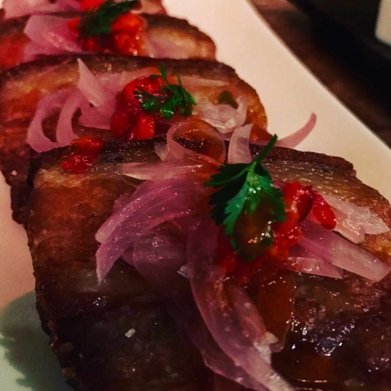 Ceviche de chicharrón, cocinado al vacío en cerveza negra, cebolla escabechada y morrón