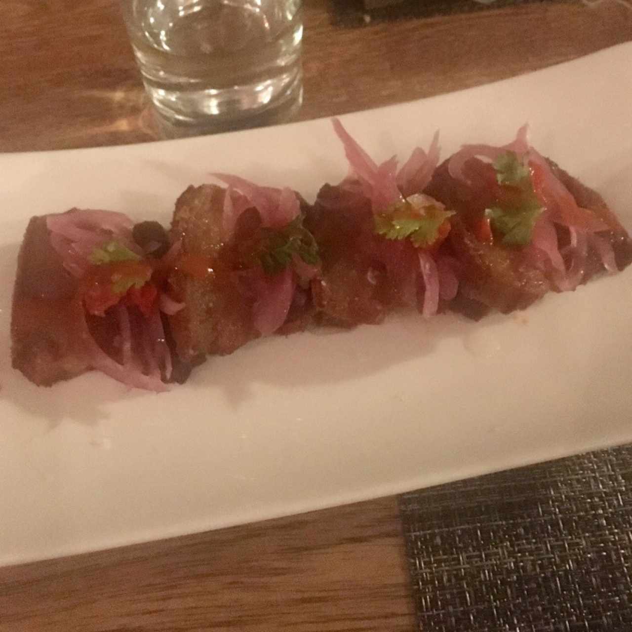 Ceviche de chicharrón, cocinado al vacío en cerveza negra, cebolla escabechada y morrón