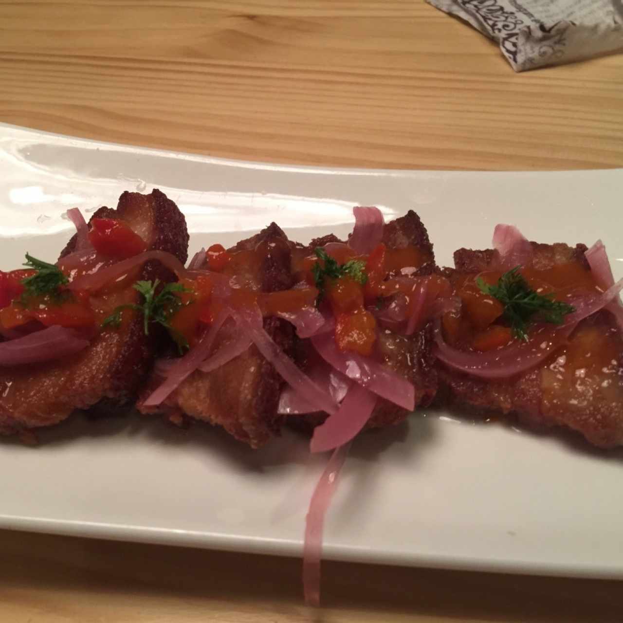 Ceviche de chicharrón, cocinado al vacío en cerveza negra, cebolla escabechada y morrón