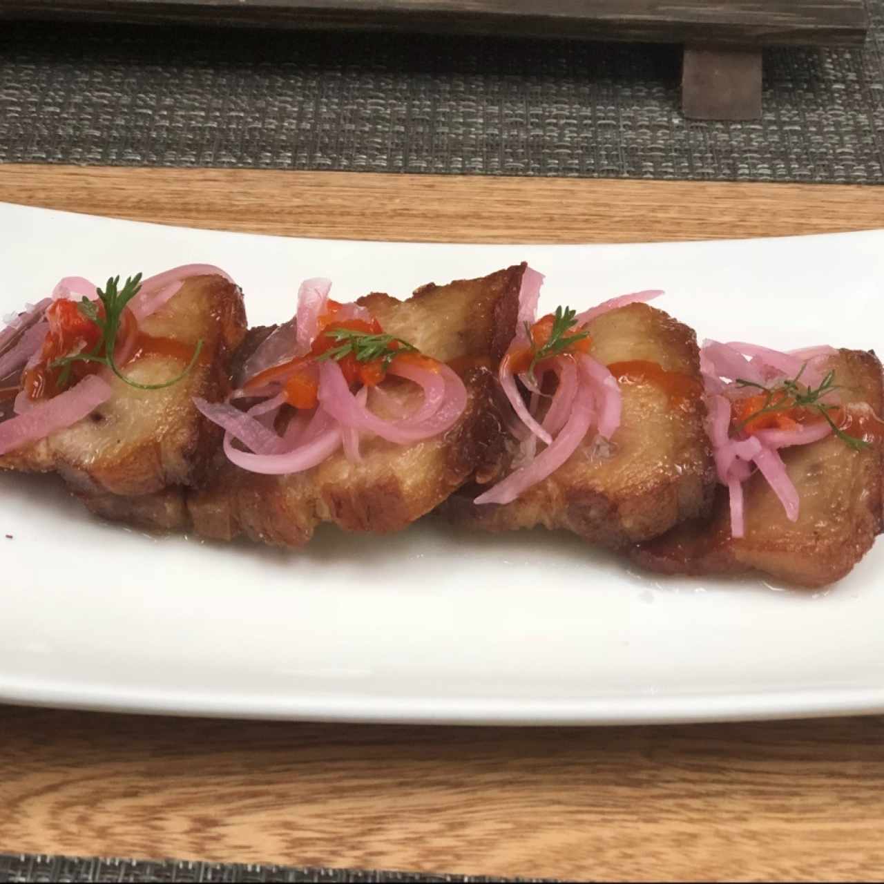 Ceviche de chicharrón, cocinado al vacío en cerveza negra, cebolla escabechada y morrón