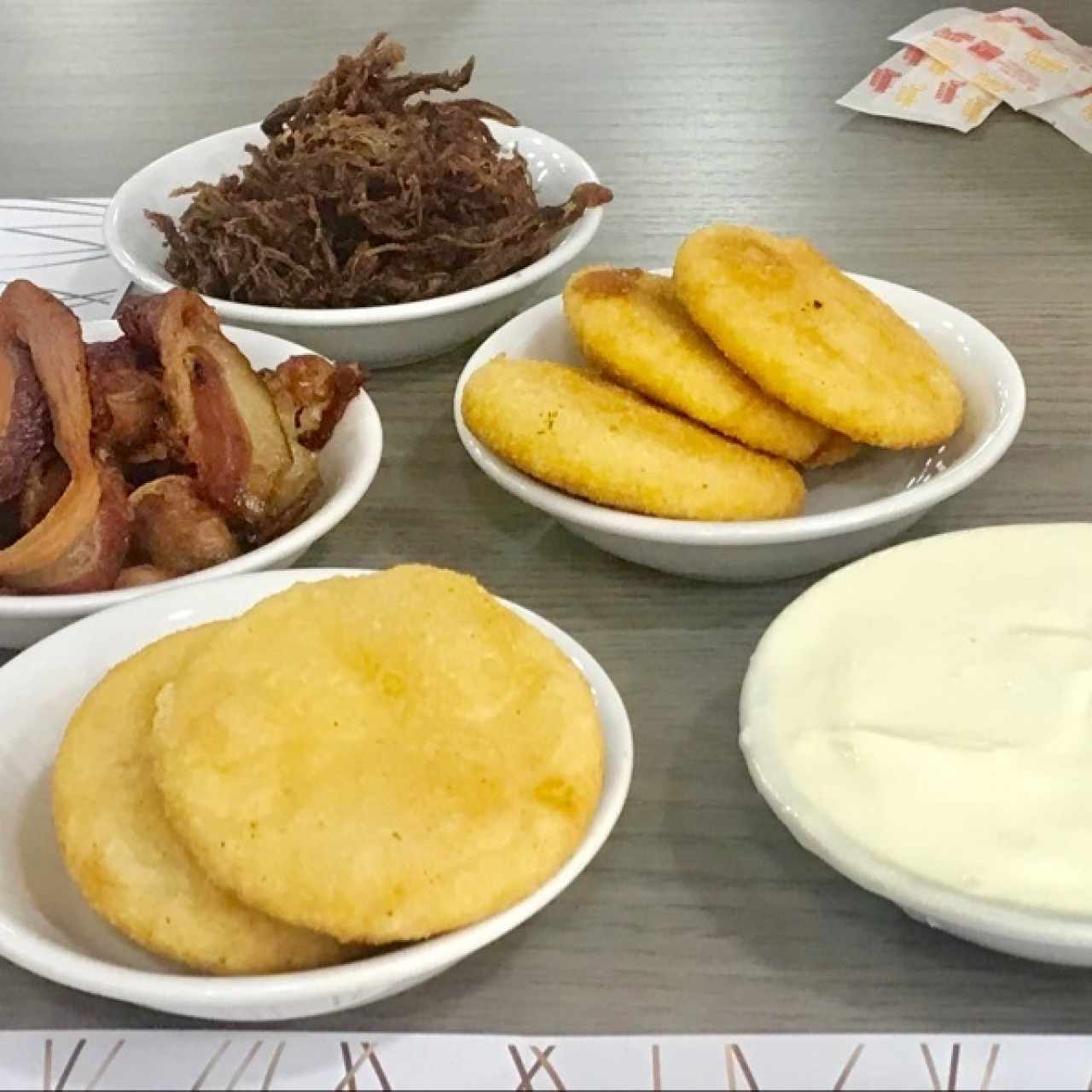 Selección de platos para el desayuno: arepas fritas, tocineta, pata de gallo y nata