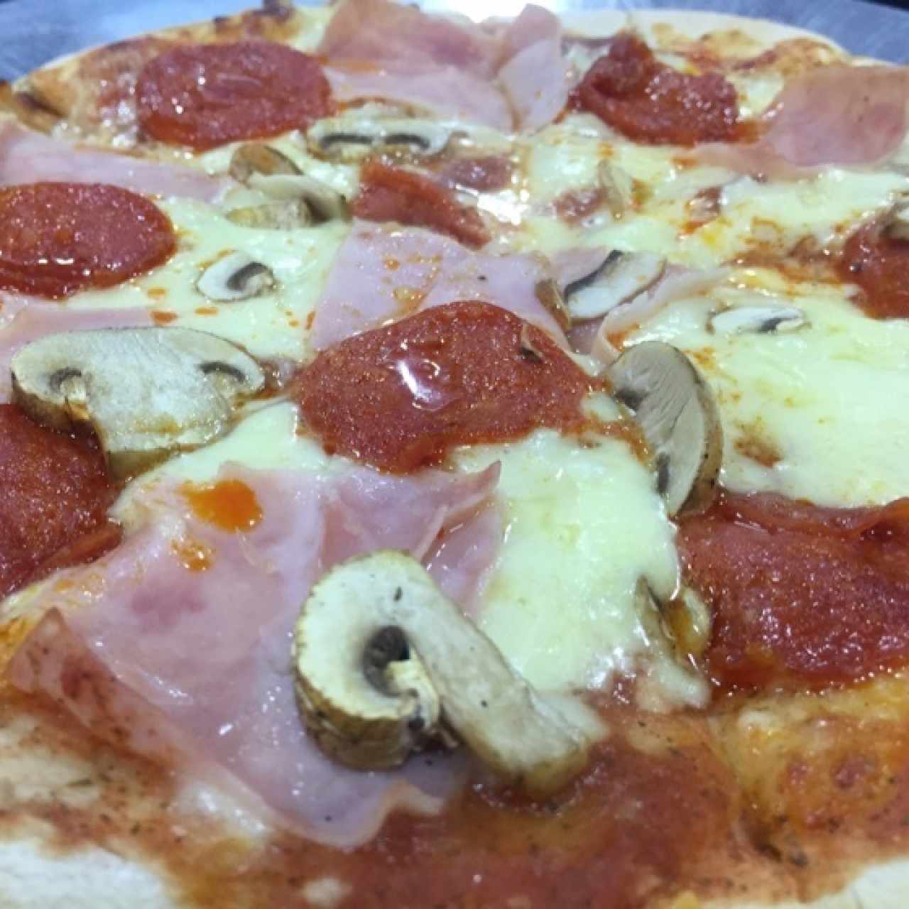 Pizza pequeña con pepperoni, jamon y champiñones