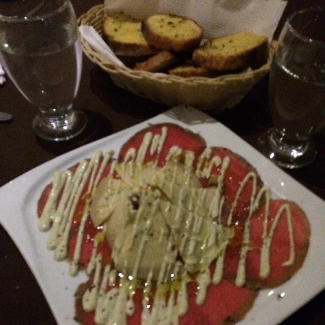Carpaccio de lomito acompañado con pan de ajo
