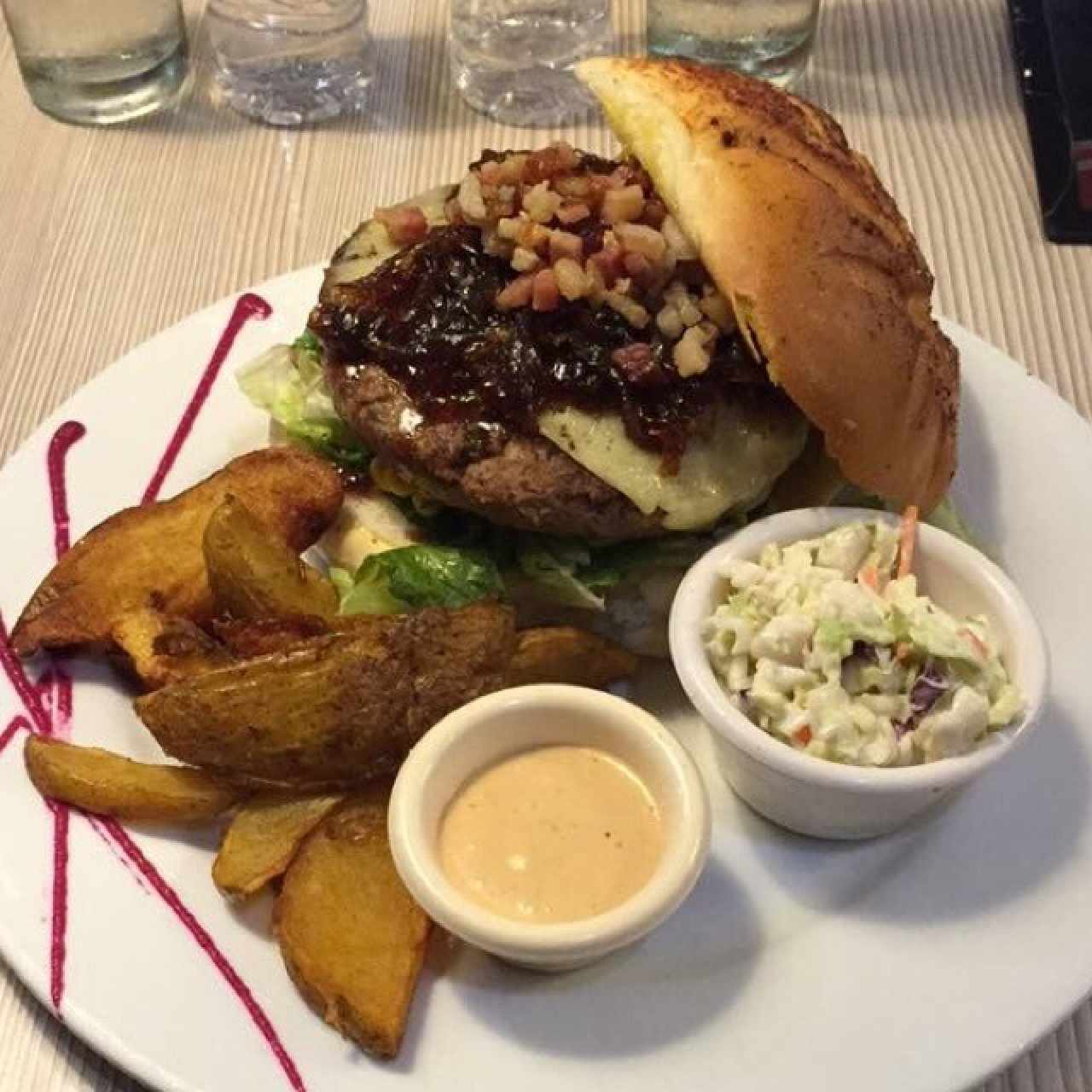 Deliciosa hamburguesa con tocineta y cebolla caramelizada, acompañada con papas fritas y cole slaw