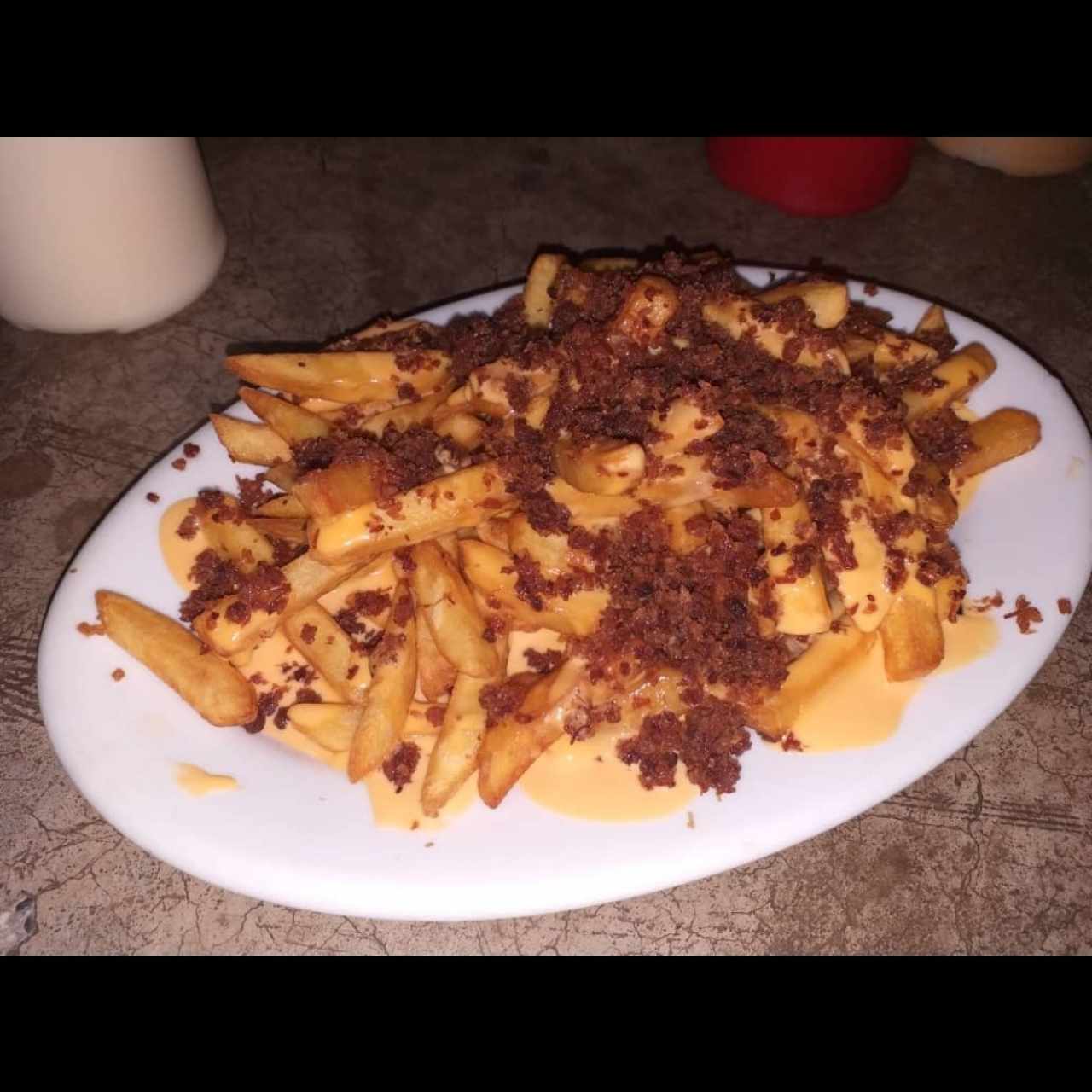 Papas con queso fundido y tocineta