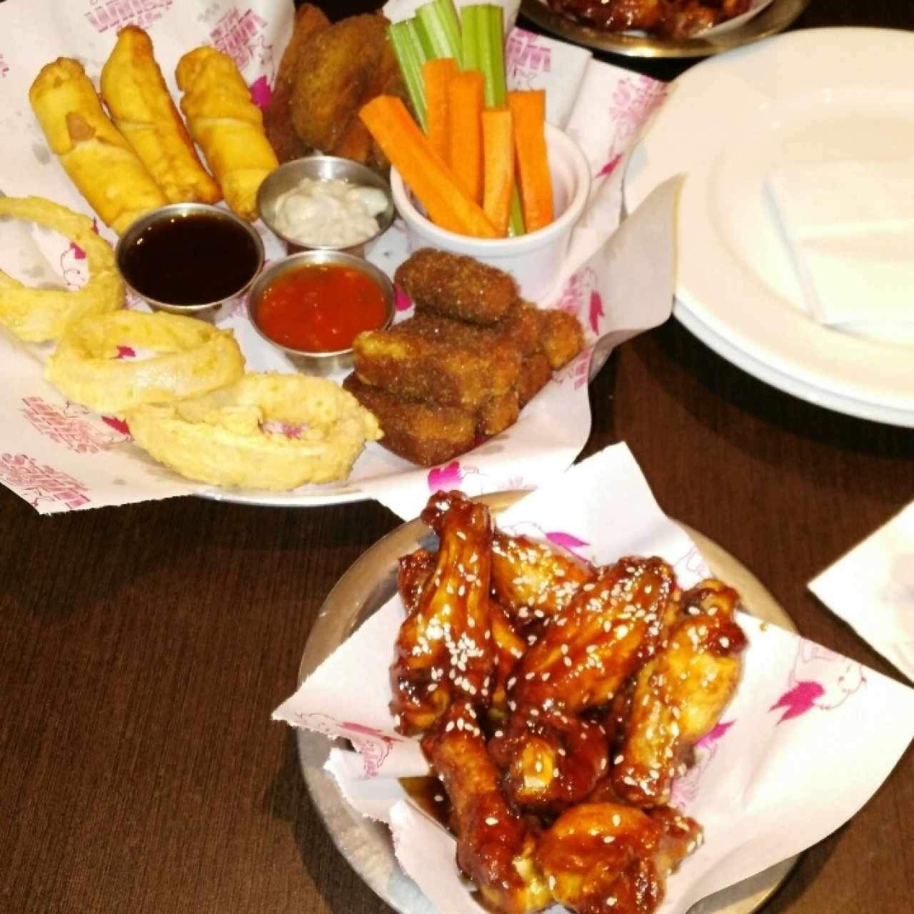 Alitas con salsa bbq picante y plato de acompañantes variados.