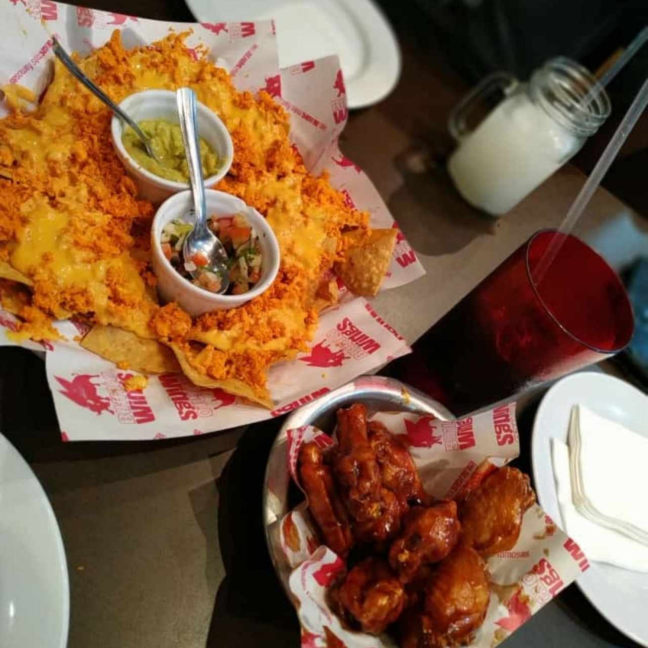 ración de nachos con queso fundido y alitas bañadas de BBQ picante