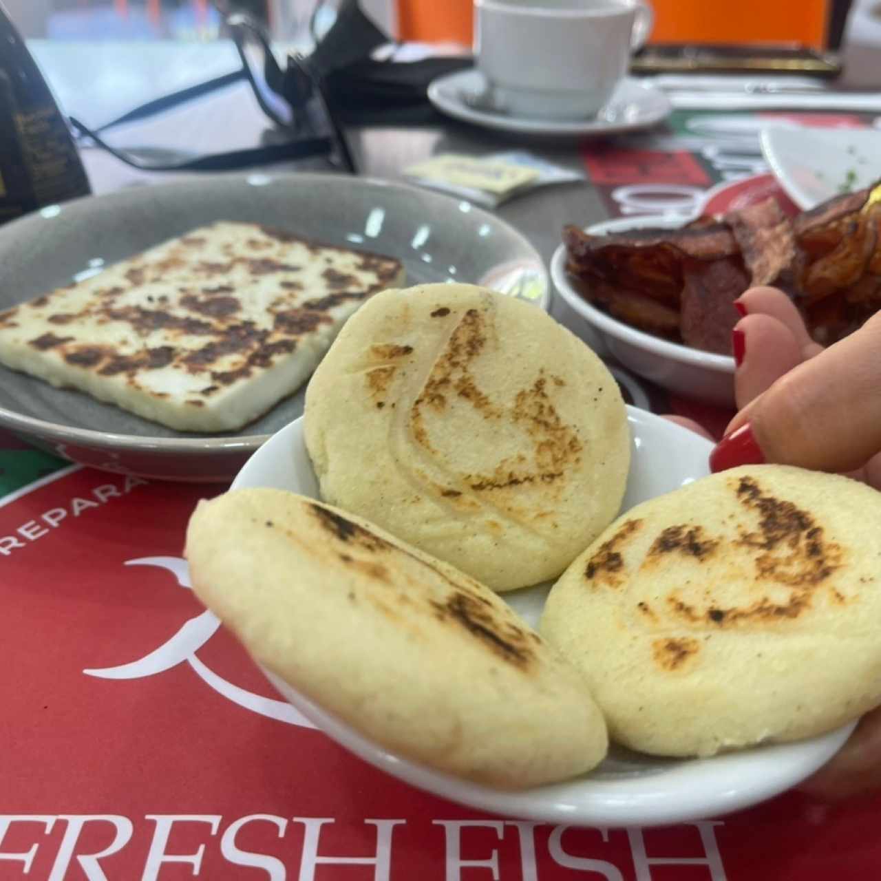 Trio de arepas pequeñas acompañadas de queso a la plancha y tocinetas