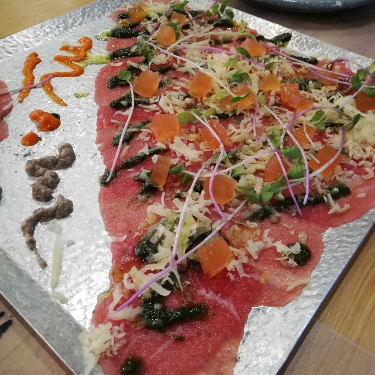 Carpaccio de res con gelatina de tomate, crema de champiñones y aji dulce con parmesano