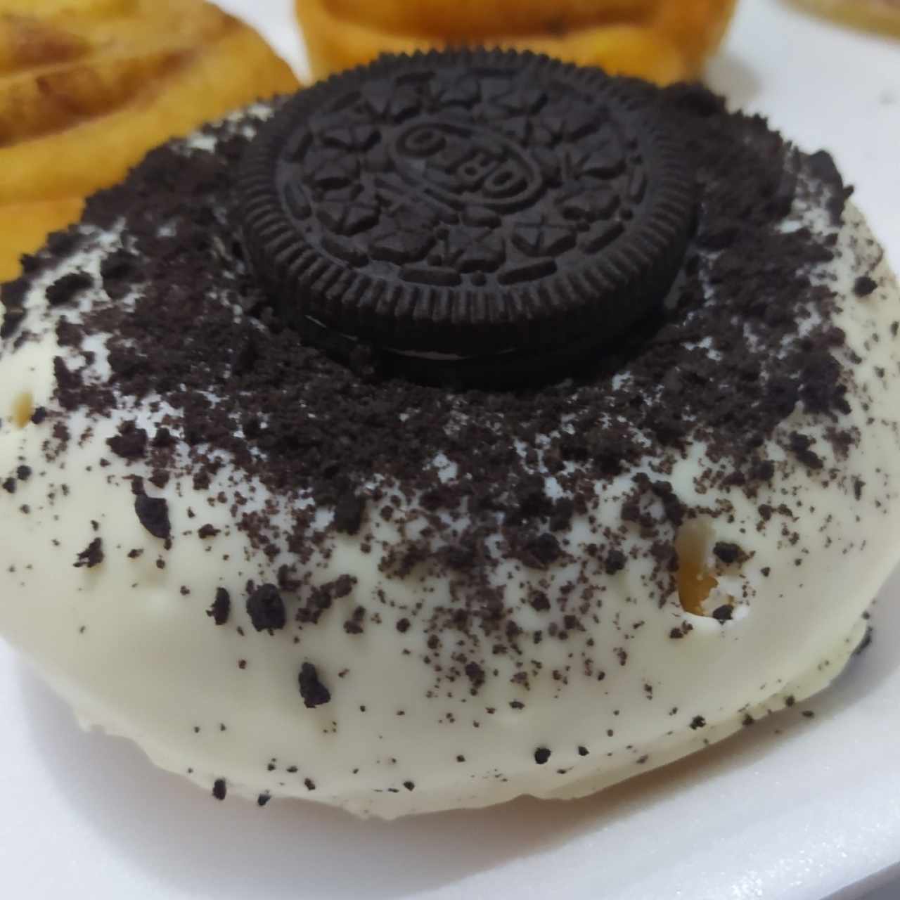 Dona cubierta de chocolate blanco con topping de oreo.