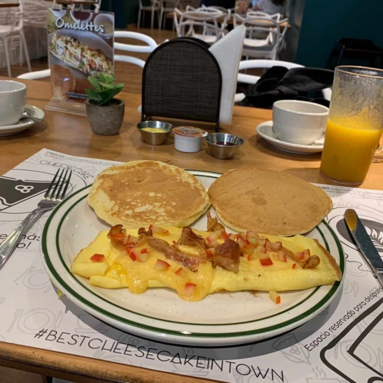 Omelette con tomates, queso y tocineta, y acompañada de panquecas